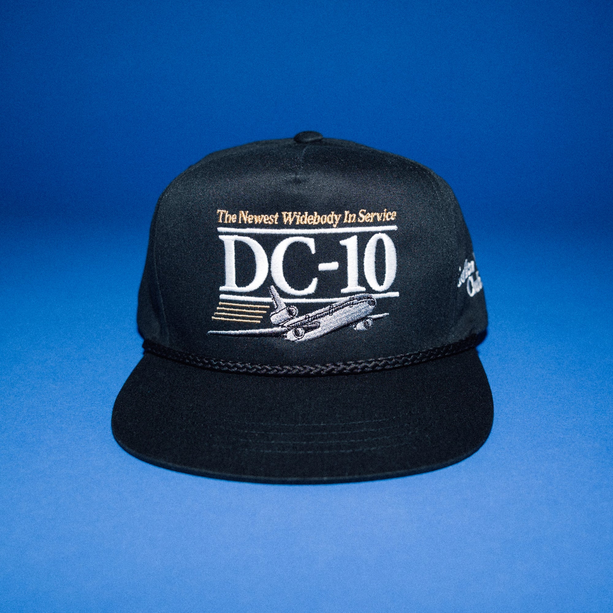 Black cap with 'DC-10' text and airplane graphic on a blue background